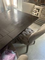 Photo showing the dark wood tabletop and part of the upholstered dining chairs around the table.