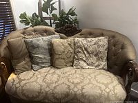 Front view of antique two-seater sofa with ornate woodwork and three cushions