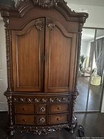 Front view of tall wooden hutch with large paneled doors and decorative carved mold work on drawers and sides