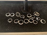 Overview showing all 15 silver rings arranged on black velvet.