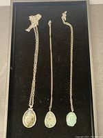 Full view of all three silver necklaces with stone pendants laid out on black velvet.