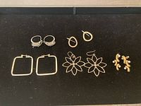Overview showing all five pairs of silver earrings displayed on a black surface.