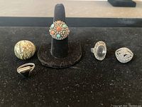 Photo of all five silver rings displayed on black velvet showing variety of designs and stones