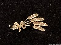 Front view of brooch showing five wheat heads and bow with seed pearl accents