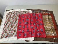 Five Liberty of London silk scarves laid out on table showing variety of patterns including florals and paisley.