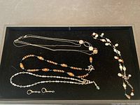 Display of four necklaces and one pair of earrings laid out on black fabric, showing overall lot contents.
