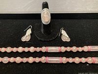 Close-up of rose quartz ring with ornate silver setting and the earrings alongside long beaded necklace showing round and rectangular rose quartz beads.