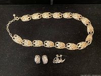 Overall view of necklace and two pairs of earrings on black background