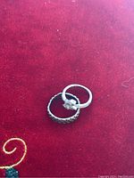 Two 925 silver rings on a red fabric background, showing varied design, one detailed with geometric accent, the other a plain band.
