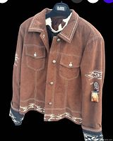 Front and side views of the brown Bogner jacket showing button closure, chest pockets, Aztec-styled trim at hem and cuffs, tribal sleeve decoration with feathers, and detailed collar stitching.