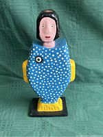 Front view of carved wooden figure with blue polka-dot body and stylized face