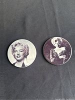 Two round Marilyn Monroe porcelain plates on black background showing different black and white portraits on each plate.