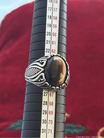Side view of vintage men's 925 silver ring highlighting the large brown stone and detailed engraved side motifs on the band.