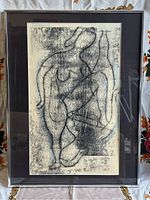 Frontal photo of framed mid century abstract print, showing the full artwork with two nude figures and surrounding black mat and silver metal frame.