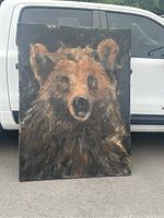 Full front view of the oil painting leaning against a white vehicle outdoors