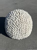 White pebble pouf ball, close-up showing textured pebble fabric surface and spherical shape.