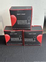 Three boxes of Riedel wine glasses stacked, showing Heart to Heart branding and promotional text.