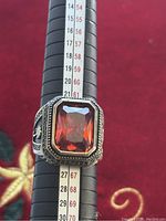 Close-up of the vintage men's silver ring on a ring sizer showing the red stone and size (around 11)