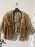 Front view of vintage Joseph Gordon mink stole on hanger showing plush fur and open front with satin lining.