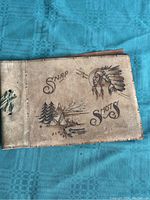 Photo of vintage photo album with leather cover showing embossed Native American chief and camping scene with text 'Snap Shots'