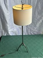 Front view of the lamp showing the full tripod base, pole, and shade.