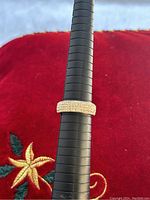 Front view of the sterling silver woman's ring size 8.5 on black ring sizing mandrel with red embroidered fabric background.