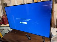 Samsung 42-inch flat screen TV showing network status message on screen with remote on surface below.