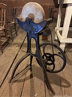 Front view of cast iron tripod stand with sharpening stone on top