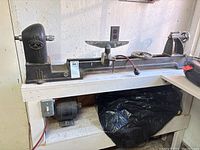 Cast iron lathe bed with headstock featuring Beaver Power Tools logo, placed on white wooden stand.