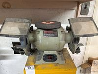 Front view of the 6-inch Supercraft bench grinder showing grinding wheels, protective shields, and power switch.