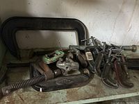 Photo showing assortment of C-clamps piled together, highlighting larger clamps measuring up to around 8 inches and smaller ones approximately 2 inches.
