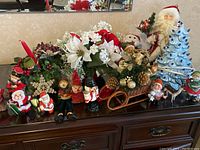 Wide view of all Christmas decorations showing Santas, faux foliage, wooden sleigh, and figurines