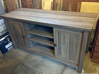 Full front view of the wooden credenza TV stand showing two side doors and three central open shelves.
