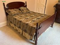 Full view of the wood framed double bed with patterned bedding showing the headboard and side rails.