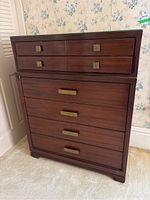Front view of a wooden dresser with 6 drawers, brass-colored handles, and a glass top protector.