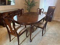 Oval dining table with four chairs arranged around it