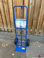 Front view of blue Mastercraft hand truck with P-shaped handle and attached product label showing specifications.
