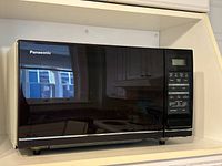 Front view of Panasonic microwave oven set in a white shelf.