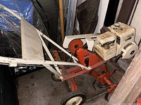 Full view of white Briggs & Stratton engine mounted on orange frame with handlebar controls of rototiller.