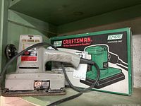 Skil Electric Sander 4900 alongside its box showing branding and power cord.