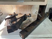 Photo showing three tow hitches including two with ball mounts and one with a locking pin secured by a clip, placed on a white surface.