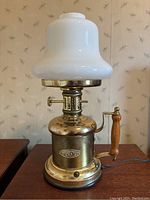 Front view of the vintage brass lamp with milk glass shade unlit showing lamp details and plaque.