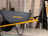 Side view of wheelbarrow showing grey bucket, yellow frame, black wheel