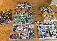 Multiple unopened baseball sticker boxes with cards displayed next to them. Boxes include 1983 with Reggie Jackson on cover and 1984 with Don Baylor on cover. Several sheets of sticker cards laid out showing baseball players.