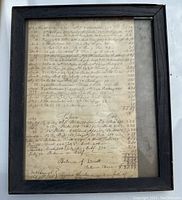Framed 1832 grocery bill showing aged handwritten document under glass with dark wooden frame, glass is dirty.