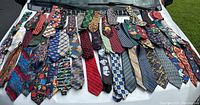 Over 50 vintage men’s neckties laid out showing varied patterns and colors including holiday and novelty themes.