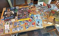 Overview of entire baseball collectible and memorabilia lot on table including cards, posters, photos, bobbleheads, and board games