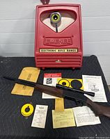 Front view of red EMENEE Electronic Rifle Range unit with toy rifle, targets, manuals, and paperwork laid out in front
