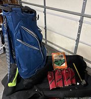 Photo showing blue golf bag, four red vintage leather head covers, vintage electronic potting pot in box, and measuring tape.