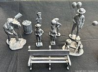 Group photo showing all nine pewter figurines arranged on black background, including man with balloons, children, photographer, garbage can, and bench.
